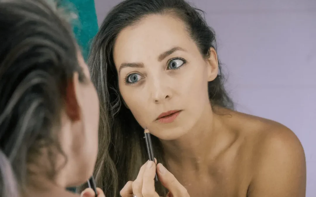 Mujer frente al espejo evaluando su rostro con serenidad, representando la elección entre tratamientos estéticos no invasivos.